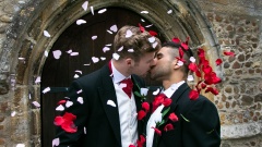 Homosexuelles Hochzeitspaar küßt sich vor der Kirche