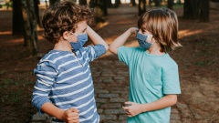 Kinder bergrüßen sich mit Ellbogen-Check und Maske