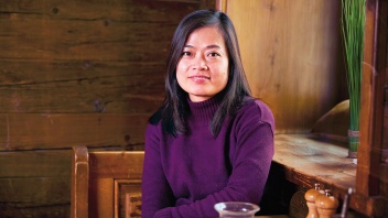 Eine vietnamesische Frau sitzt in einer Stube mit holzgetäfelten Wänden