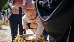 Ein Kind wird mit dem Wasser des Sees getauft