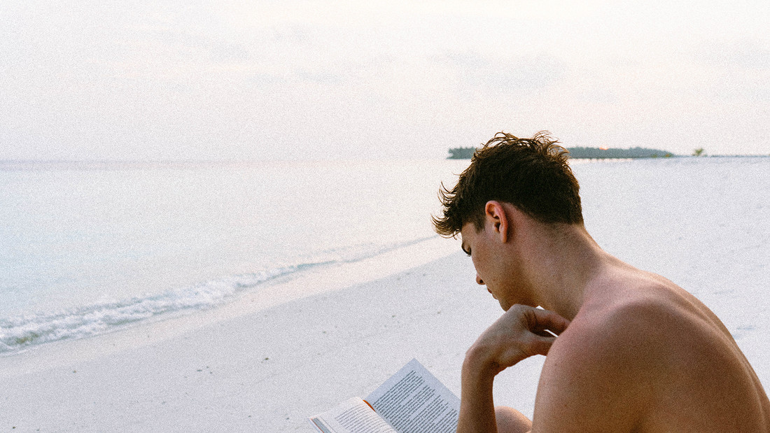Mann liesst einsam am Strand