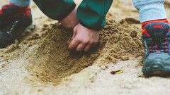 Kind gräbt im Sand