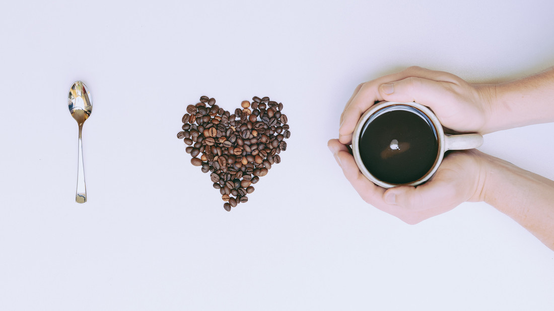 Löffel, Kaffeebohnen in Herzform und eine Kaffeetasse 