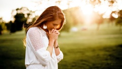 Frau betet im Sonnenschein
