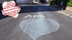 Ein blaues Herz und der Schriftzug AfD sind mit Kreide auf eine Straﬂe 
