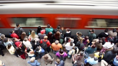 Menschen warten am Bahnhof auf einen einfahrenden Zug.