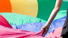 Frauenhand an einer Regenbogenflagge.